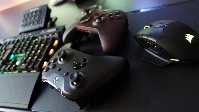 Due controller Xbox accanto a una tastiera illuminata e a un mouse da gioco